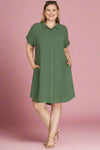 Woman wearing a green button up shirt dress against a plain background