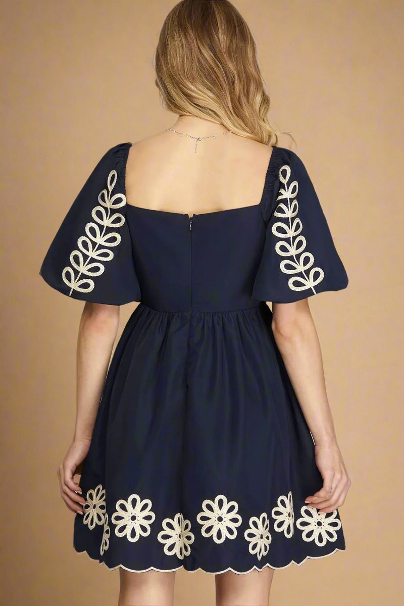 Navy blue dress with white floral embroidery on a plain background