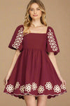 Maroon dress with floral and leaf patterns on a plain background