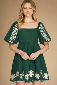 Green dress with white floral embroidery on a plain background