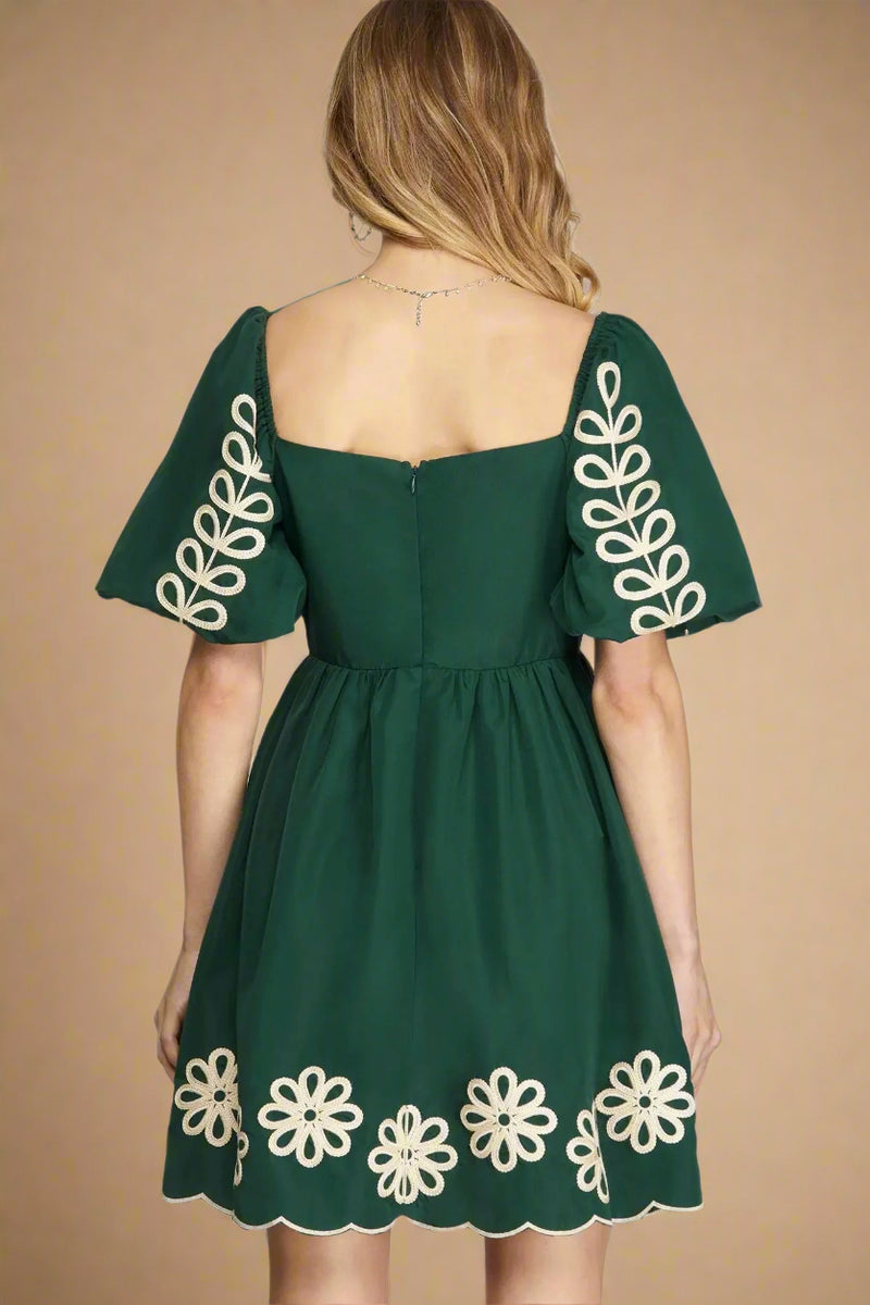 Green dress with white floral embroidery on a plain background