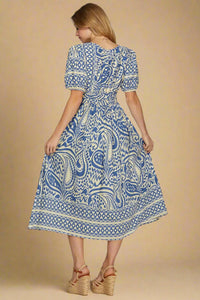Woman wearing a blue and white patterned dress on a plain background