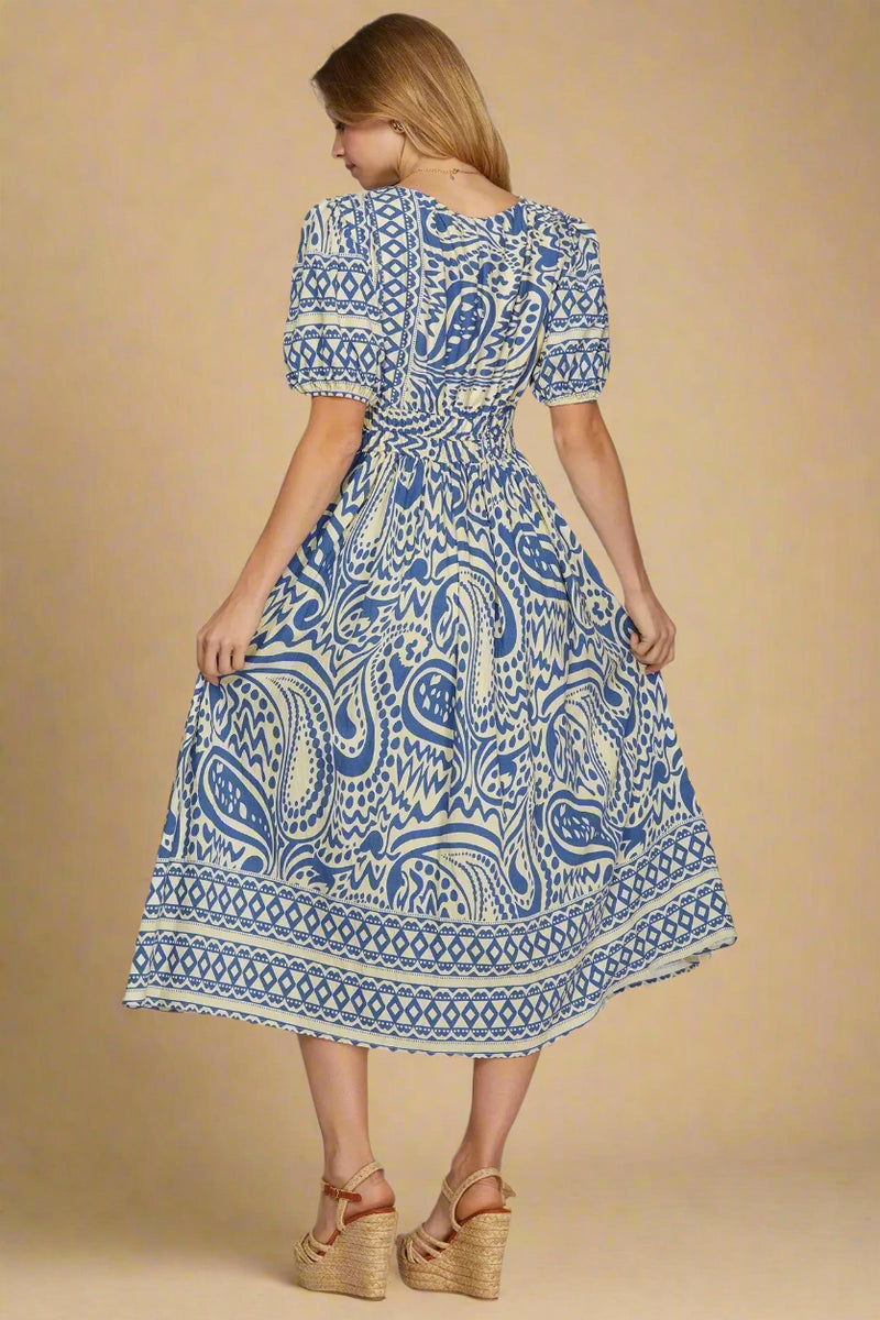 Woman wearing a blue and white patterned dress on a plain background