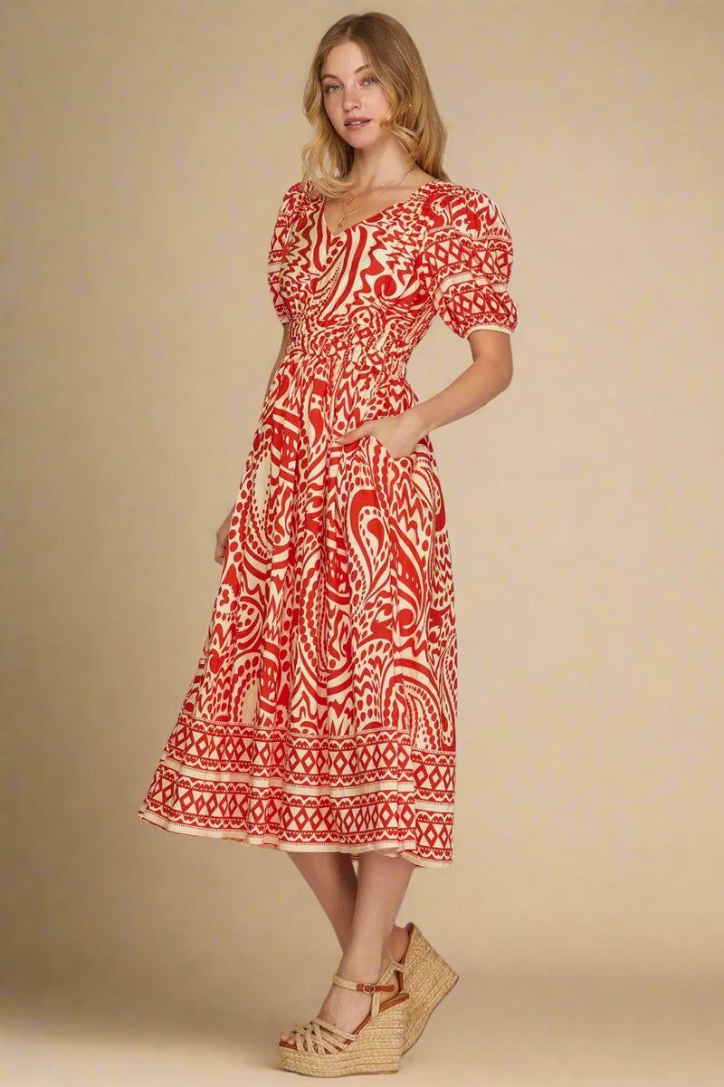 Woman wearing a red and white patterned dress on a plain background