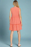 Woman wearing a coral dress on a plain background