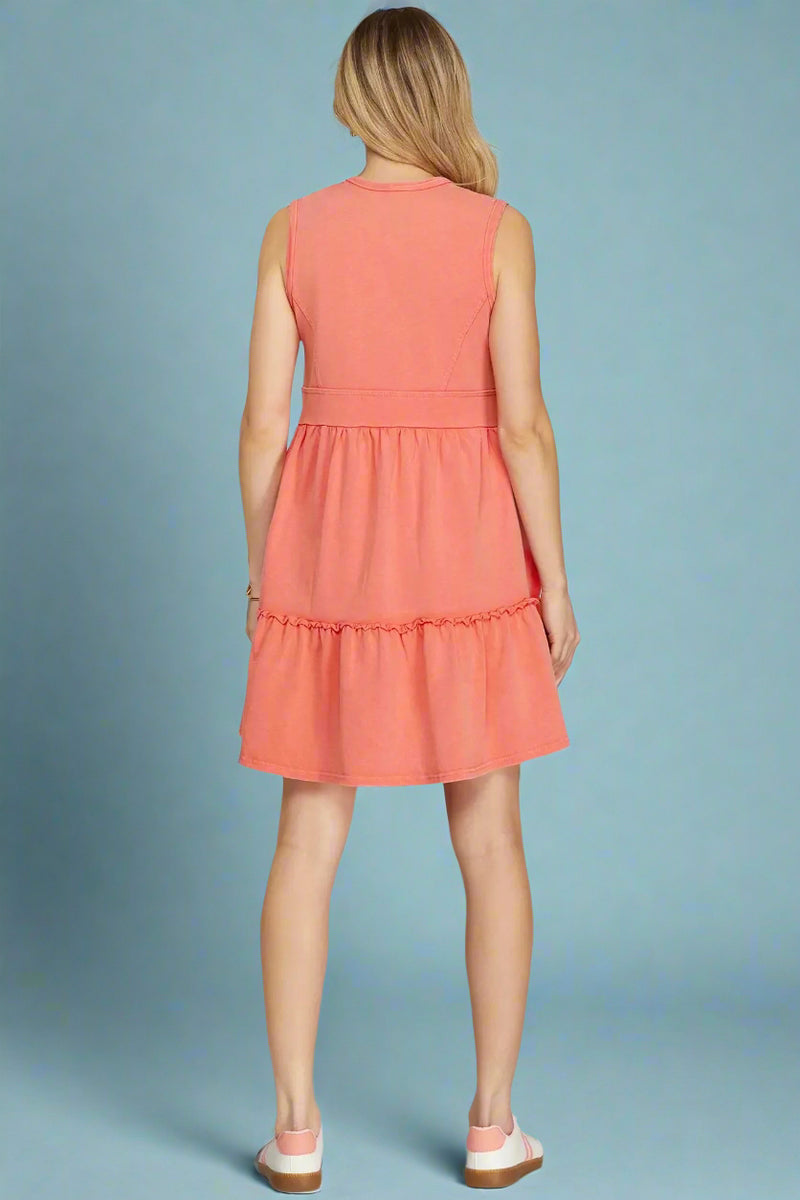 Woman wearing a coral dress on a plain background