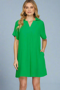 Woman wearing a green dress against a plain background.