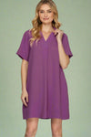 Woman wearing a purple dress against a plain background.