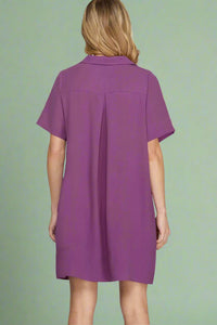 Purple dress worn by a person on a plain background.
