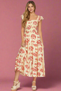 Woman wearing a red and cream floral dress on a plain background