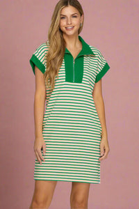 Woman wearing a green and white striped dress with a collar on a plain background