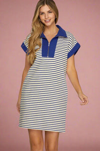 Woman wearing a striped dress with blue accents on a plain background