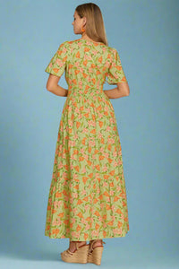 Woman wearing a green floral dress on a plain background