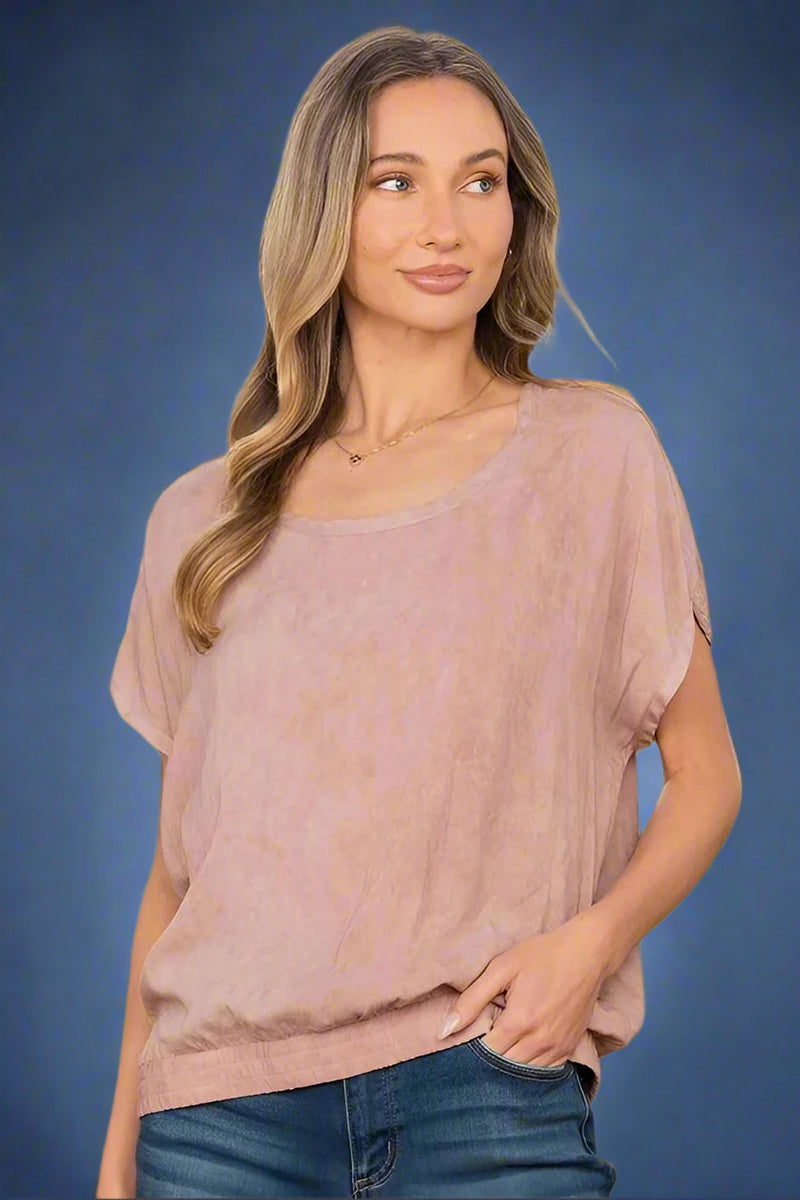 A relaxed fit mauve top. It has unique short sleeves and a ribbed waist bad.