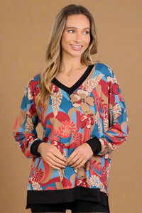 A women’s lightweight, relaxed fit long sleeve v-neck blouse featuring a floral print in blues, reds, and tans. Hems and neckline lined with black trim.