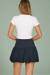 Person wearing a white top and navy skirt on a plain background