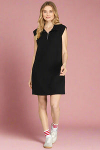 Woman wearing a black sleeveless dress on a plain background