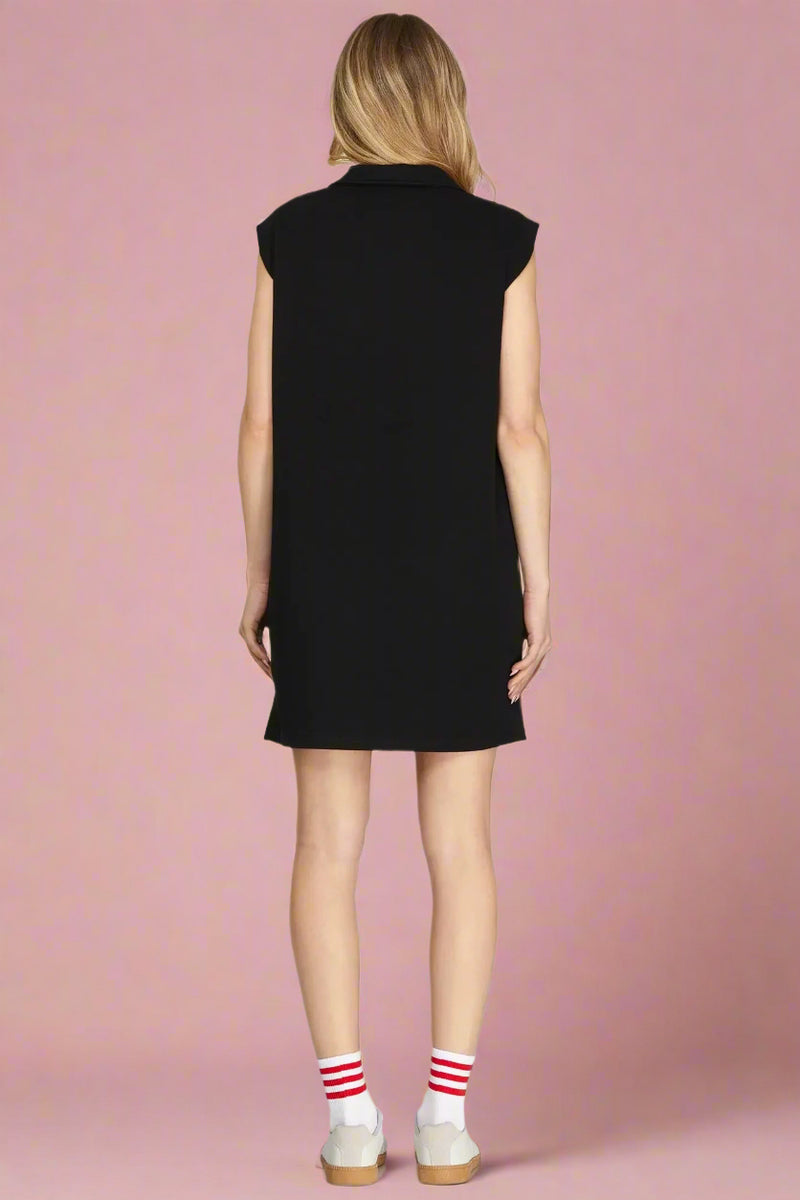 Woman wearing a black sleeveless dress on a plain background