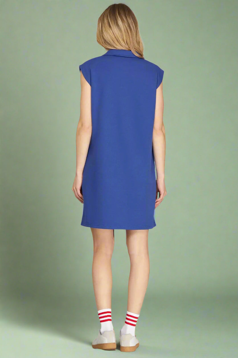 Woman wearing a blue sleeveless dress on a plain background