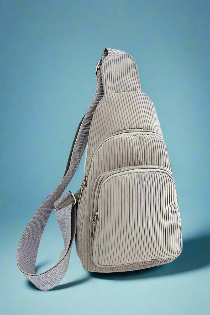 Classic sling bag in a soft grey corduroy. Features two separate compartments and an adjustable canvas strap.