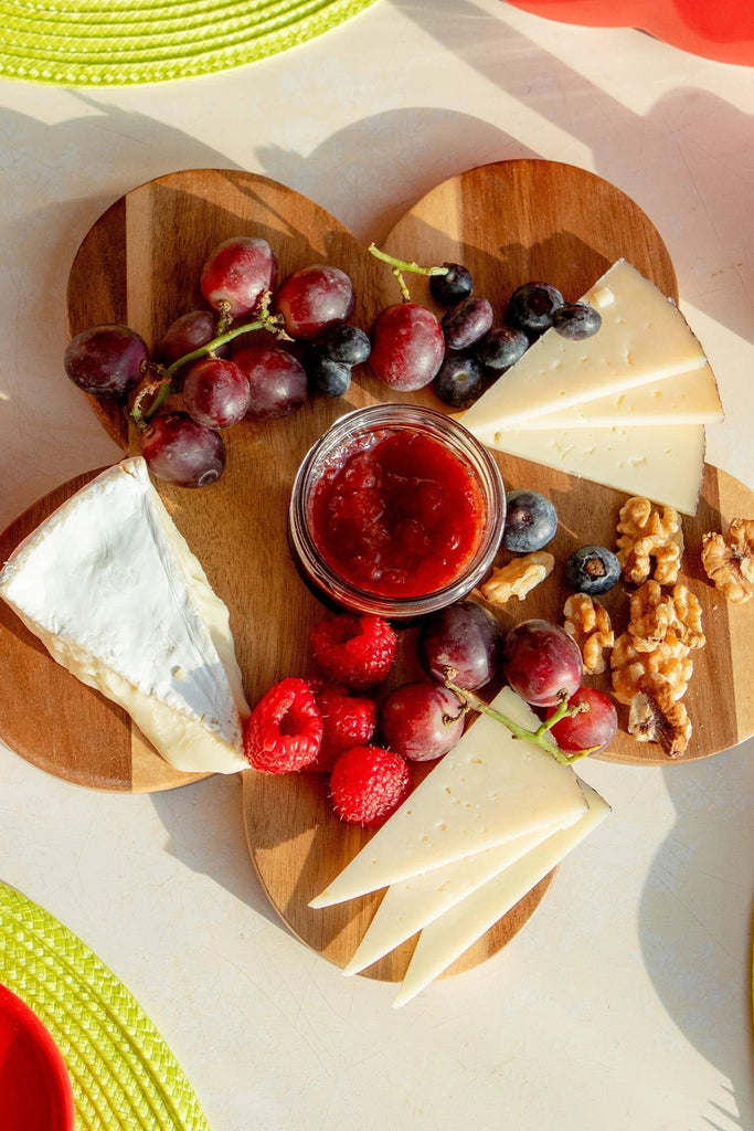 A daisy shaped wooden charcuterie board with cut out in middle.