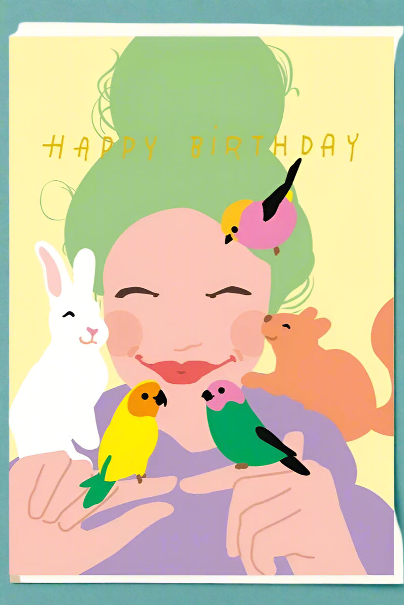 A greeting card with the image of a woman with birds, a bunny, and a squirrel on here and text that reads ‘Happy Birthday’.