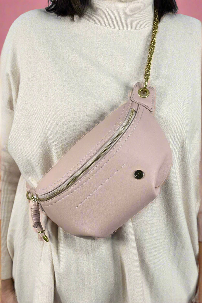 A light pink Fanny pack belt with gold chain strap and zipper enclosure.