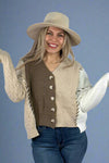Model is wearing a long sleeve mixed knit cardigan. The cardigan has medium sized buttons, contrasting exposed stitch details and an asymmetrical hem. With a slight crop it hits at hip length. 