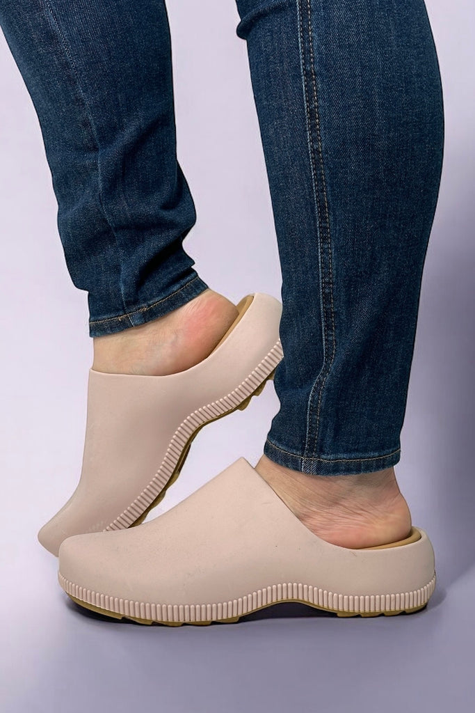 Model is wearing light pink colored rubbed clogs. 