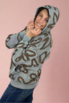 A women’s long sleeve zip up hoodie in washed blue color featuring bold floral print in brown.