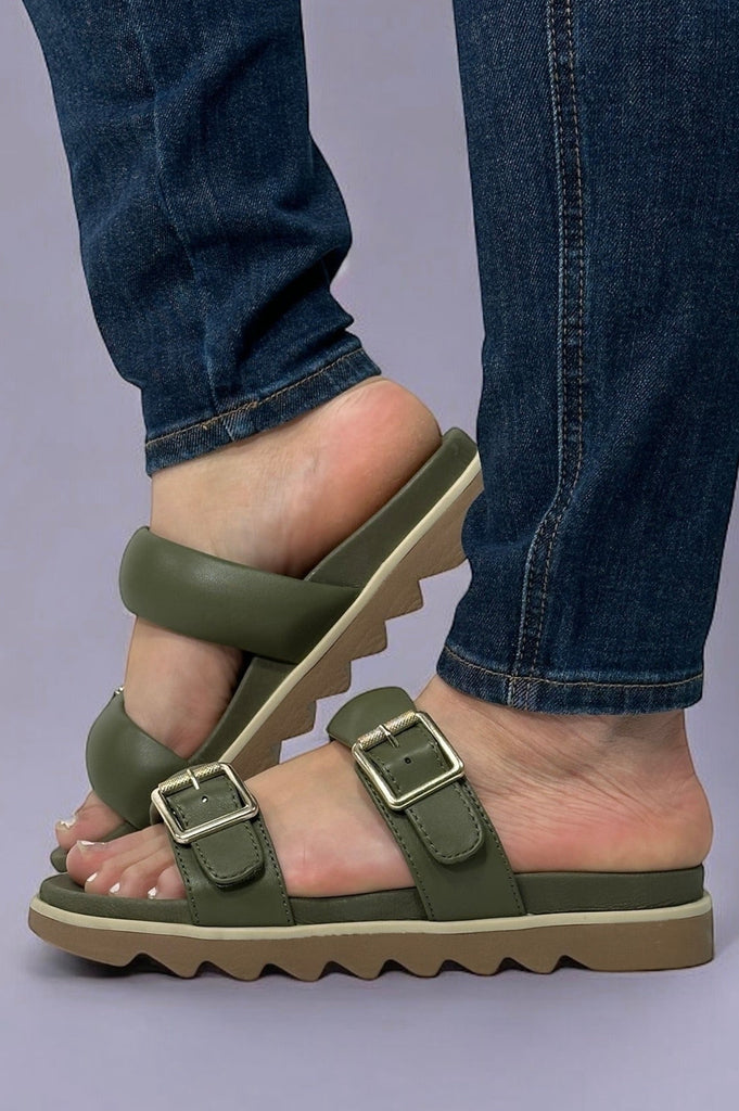 Model is wearing olive colored leather double strap slip on sandals.