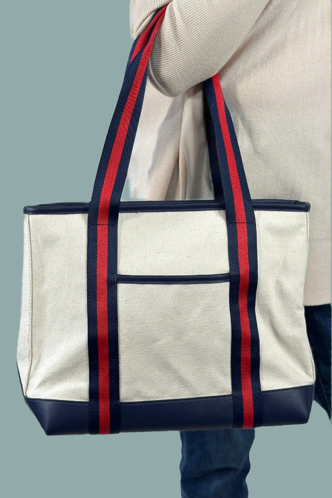 Classic white canvas tote style purse with navy accents and a navy and red durable shoulder straps.