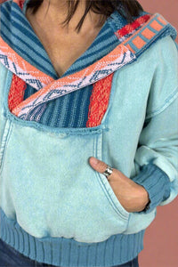 A women’s hooded sweatshirt in a light blue with contrasting knit hood and neckline.