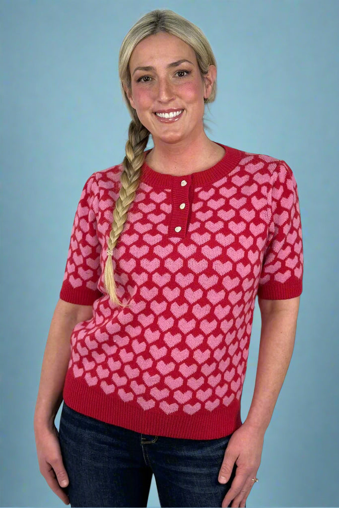 Short sleeve knit henley sweater with red and pink heart pattern all over. Subtle puff sleeves and heart button details. Feminine and playful. 