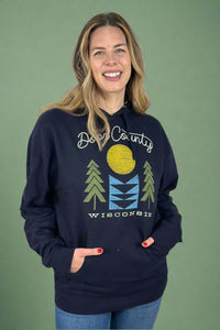 A unisex hooded sweatshirt in navy blue with kangaroo pocket and exclusive Door County Wisconsin graphic of geometric trees, sun, and water on the front.