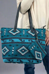Model is holding a western printed tote bag with an attached wristlet. 