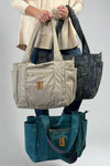 A tote bag by New Hope Girls, in dream, tan, or slate colors. Has a trolly sleeve and zipper closures. 