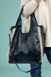 Model is wearing a slouchy black hobo bag with rattan detailing on the sides. 
