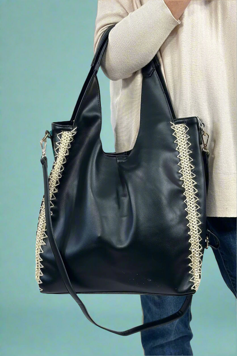 Model is wearing a slouchy black hobo bag with rattan detailing on the sides. 