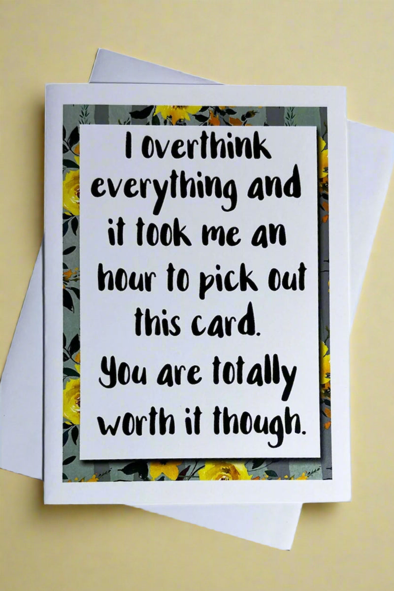 A white card with floral border that says “I overthink everything and it took me an hour to pick out this card. You are totally worth it though.”