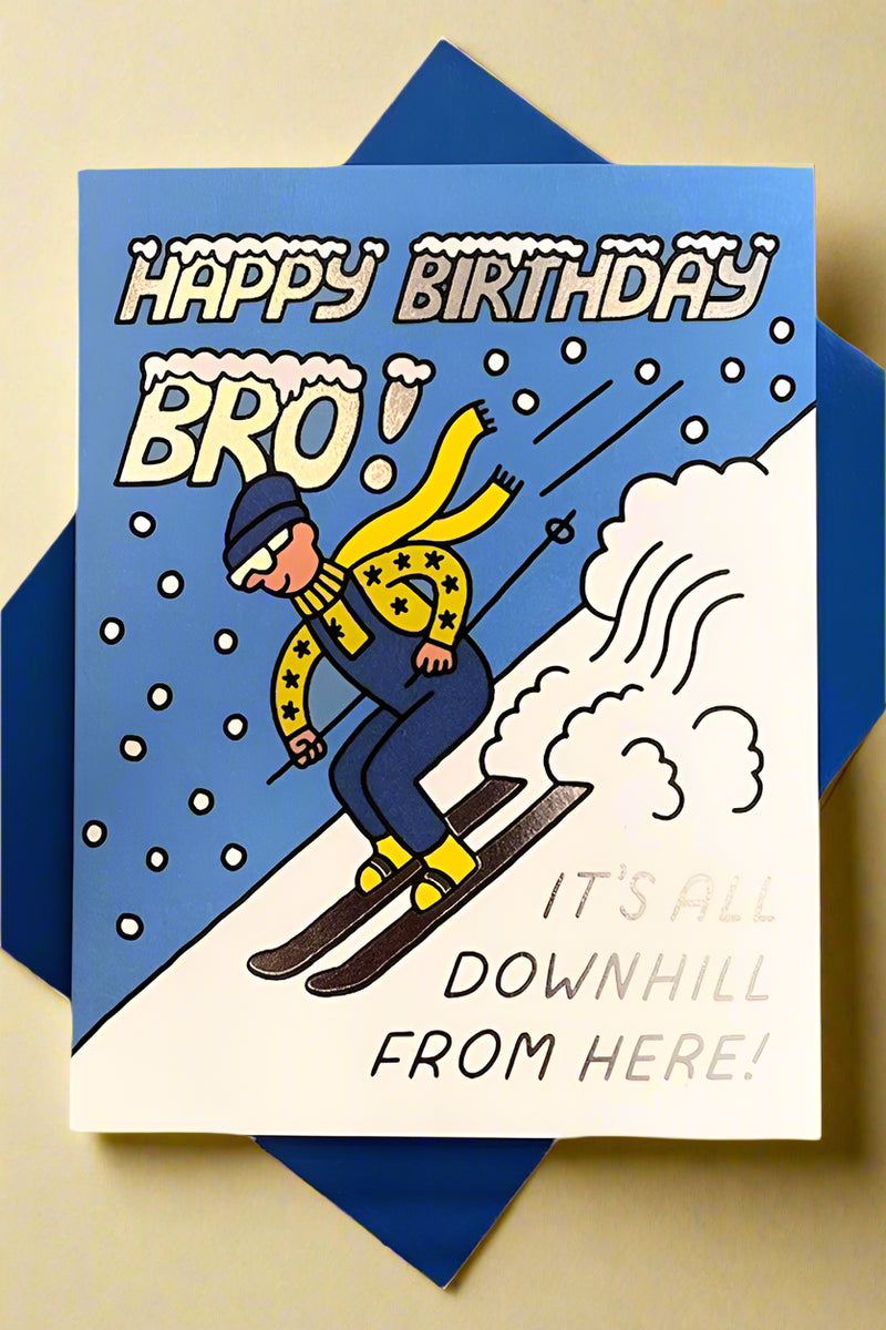 Birthday card with image of a downhill skier and text that reads ‘Happy Birthday Bro! It’s All Downhill From Here!’ with blue envelope.