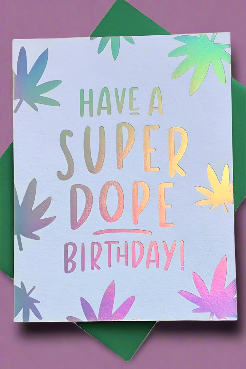 A greeting card with silver foil stamped marijuana leaves and text that reads ‘Have A Super Dope Birthday!’