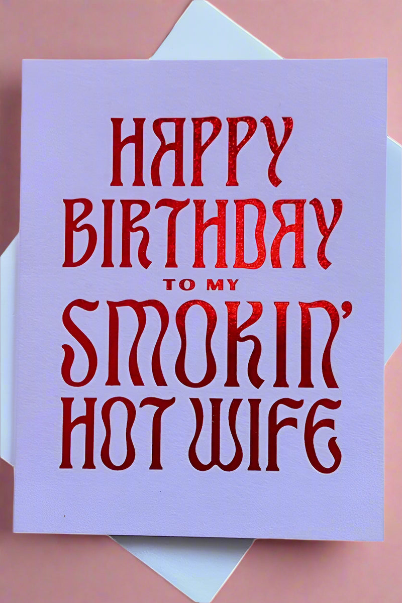 A light purple greeting card with red foil stamped text that reads ‘Happy Birthday to my Smokin’ Hot Wife’.