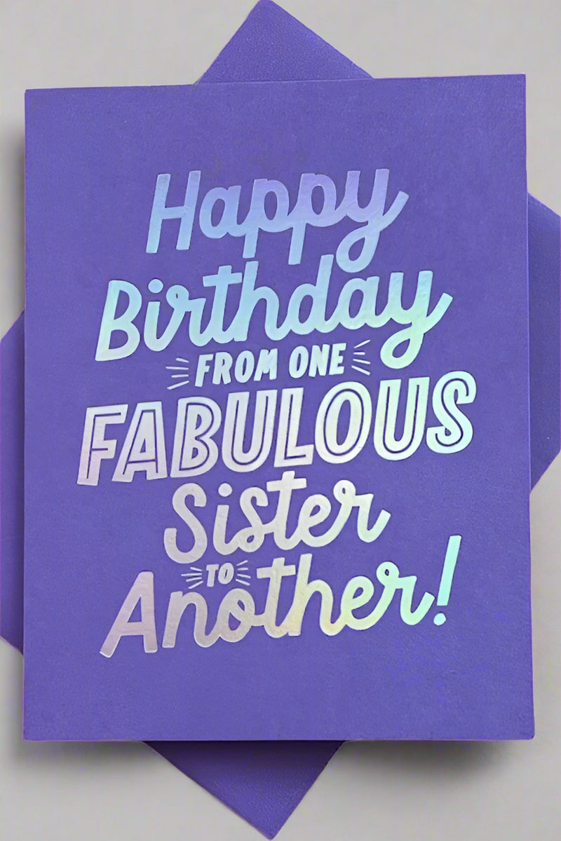 A solid purple greeting card with metallic silver text that reads ‘Happy Birthday From One Fabulous Sister To Another!’