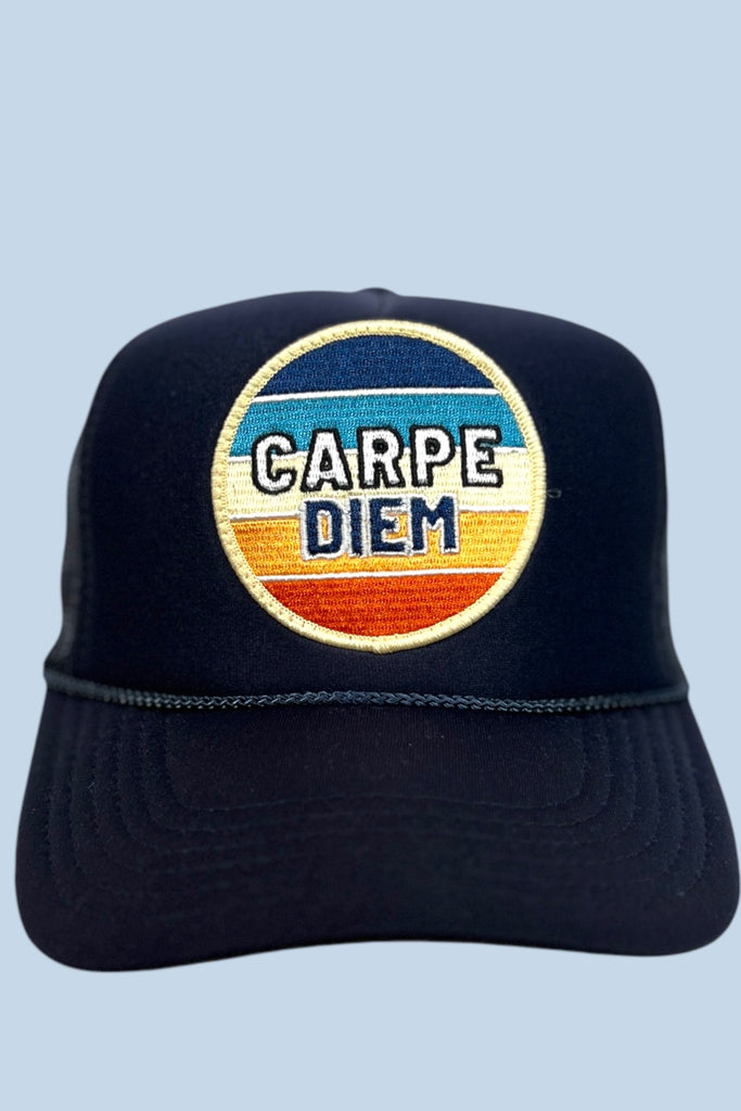 Navy colored trucker hat with a colorful patch that says "CARPE DIEM" on the front panel.