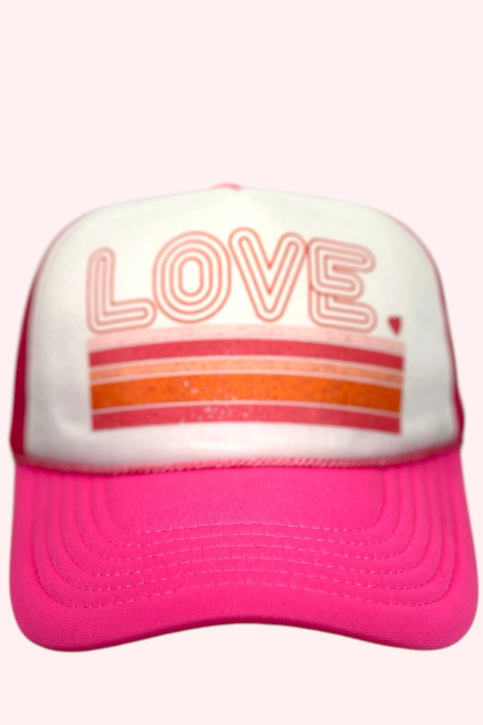 Pink and white foam front trucker hat with the word "LOVE" printed across the front panel in retro lettering.