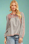 A striped long sleeve top with flower embroidery around the neckline, sleeves, and hem.