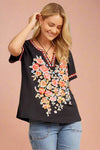 A short sleeve black top with colorful floral embroidery.