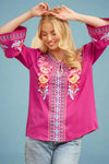 A women’s relaxed fit bell-sleeve blouse in a vibrant magenta featuring a split scoop neck and floral embroidery along front and sleeves.