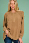 A women’s relaxed fit long sleeve henley top in a heathered camel color.